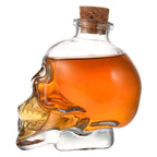 Licorera calavera de cristal sola con licor ambar sobre fondo blanco