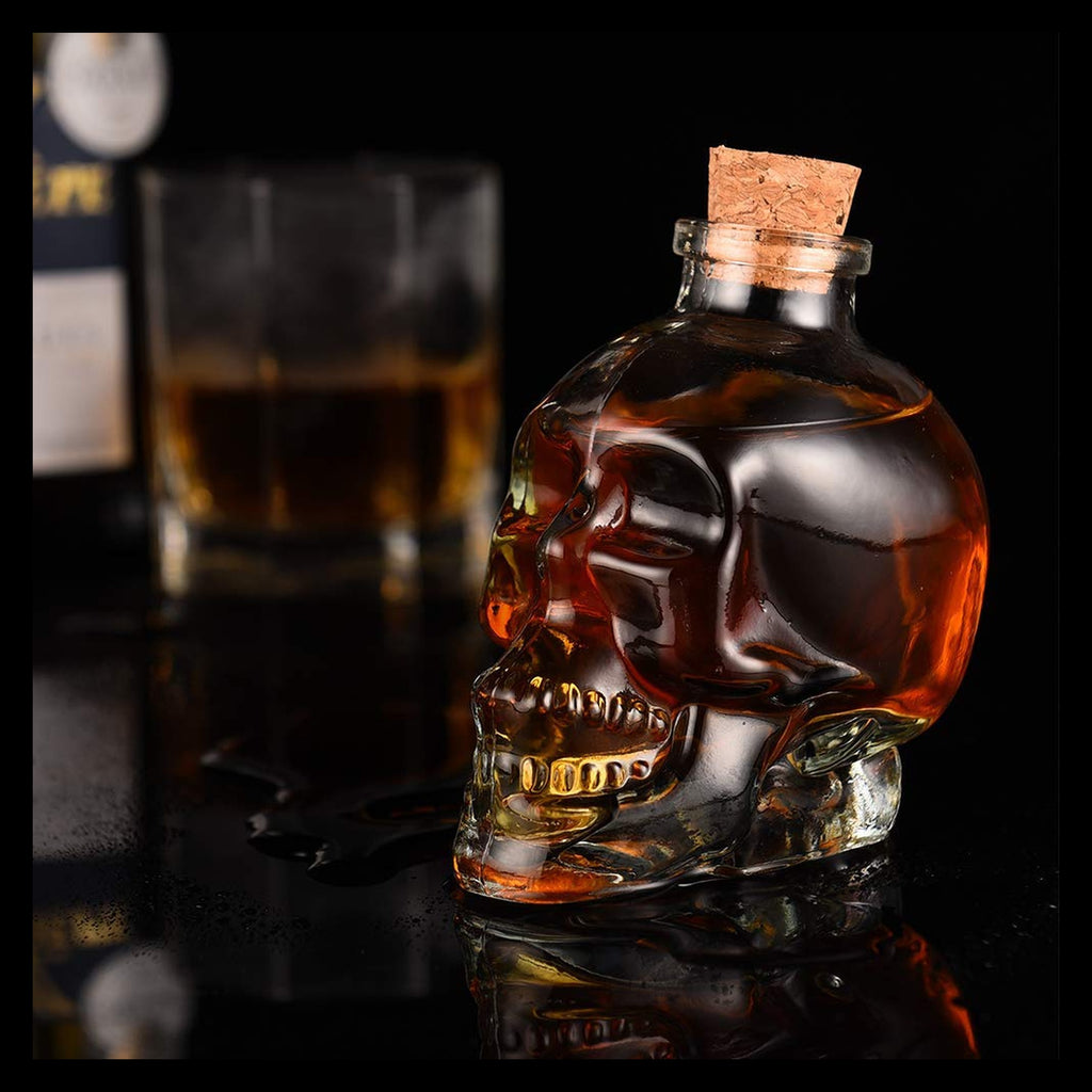 Licorera calavera con whisky sobre mesa oscura junto a vaso y botella